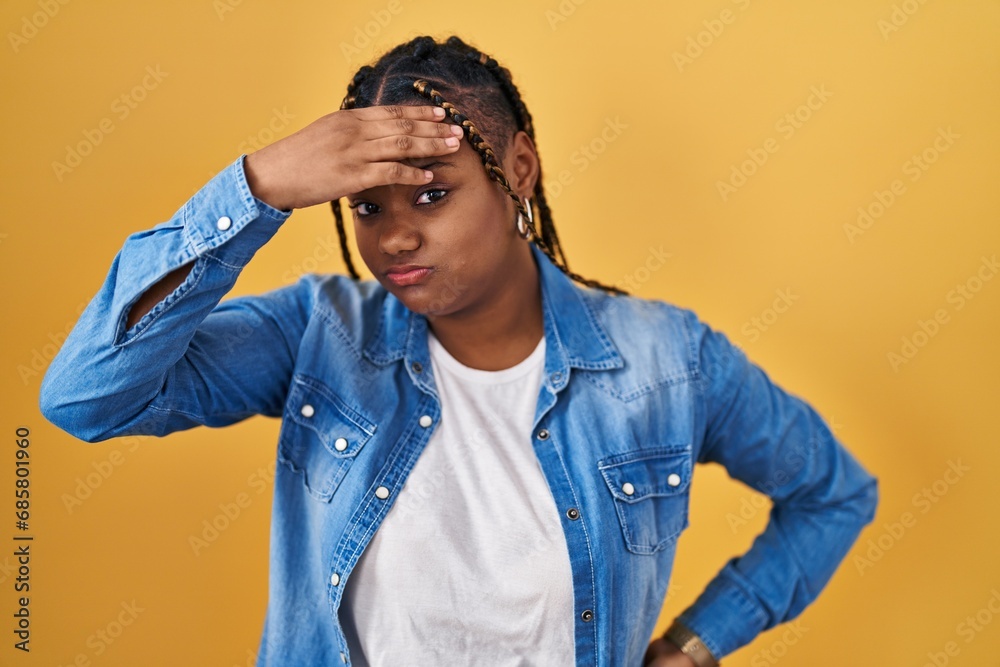 African american woman with braids standing over yellow background worried and stressed about a problem with hand on forehead, nervous and anxious for crisis African american woman with braids standing over yellow background worried and stressed about a problem with hand on forehead, nervous and anxious for crisis