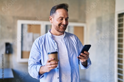 Young caucasian man using smartphone drinking coffee at street © Krakenimages.com