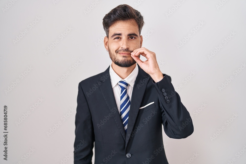 Young hispanic man with tattoos wearing business suit and tie mouth and lips shut as zip with fingers. secret and silent, taboo talking Young hispanic man with tattoos wearing business suit and tie mouth and lips shut as zip with fingers. secret and silent, taboo talking