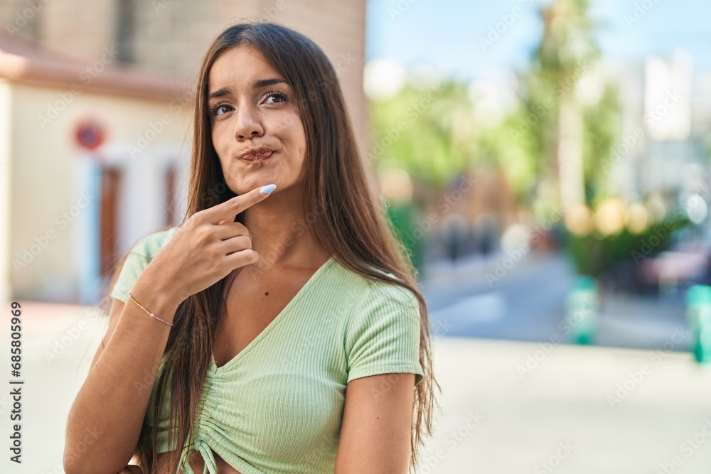 Young beautiful hispanic woman standing with doubt expression at street