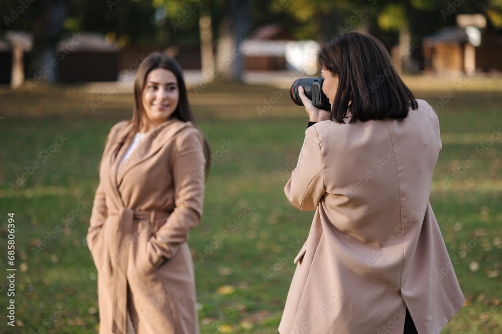 Process of woman photographer make a photo for gorgeous female in park Process of woman photographer make a photo for gorgeous female in park