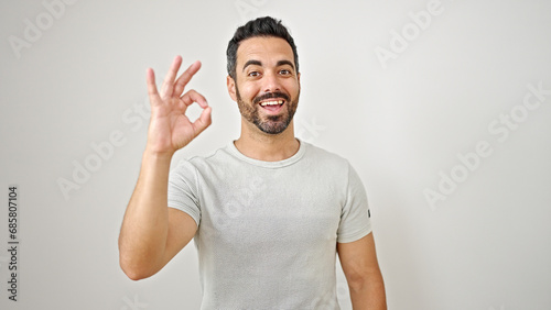 Obraz na płótnie Young hispanic man smiling with doing ok gesture over isolated white background