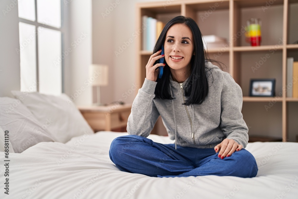 Young caucasian woman talking on smartphone sitting on bed at bedroom Young caucasian woman talking on smartphone sitting on bed at bedroom