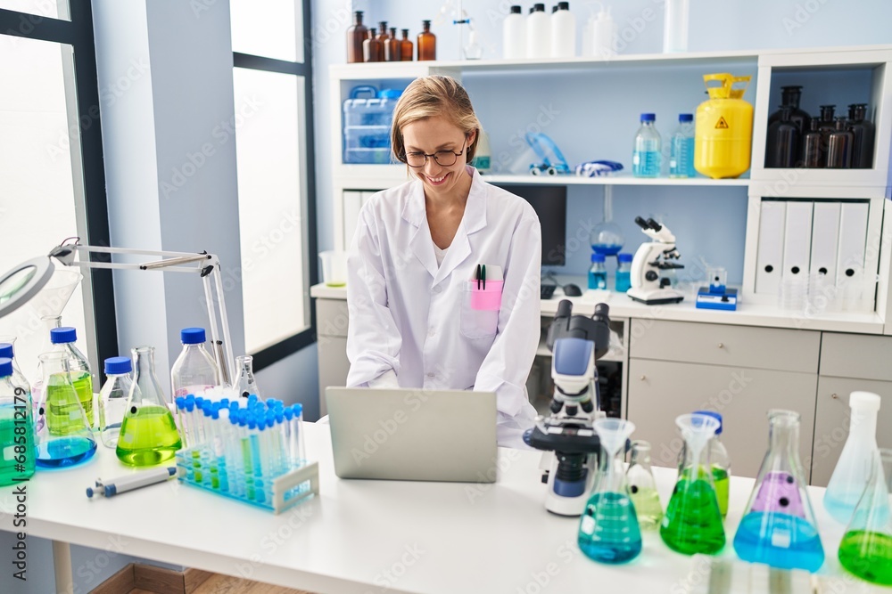 Young blonde woman scientist smiling confident using laptop at laboratory Young blonde woman scientist smiling confident using laptop at laboratory