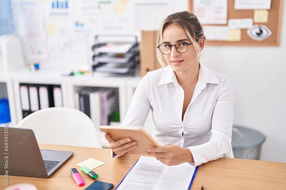 Young blonde woman business worker reading notebook at office