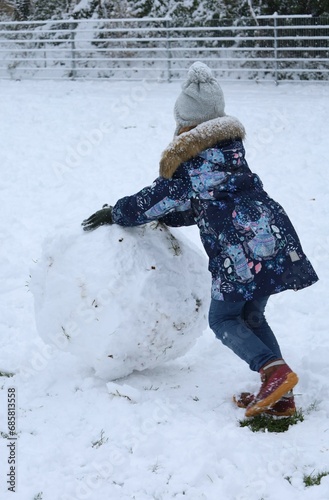 child playing with snow and rolling a snow globe
