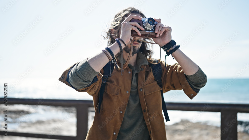 Obraz premium Young hispanic man tourist wearing backpack make photo at seaside