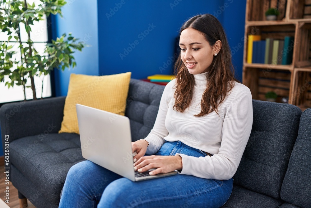 Young beautiful hispanic woman using laptop sitting on table at home Young beautiful hispanic woman using laptop sitting on table at home