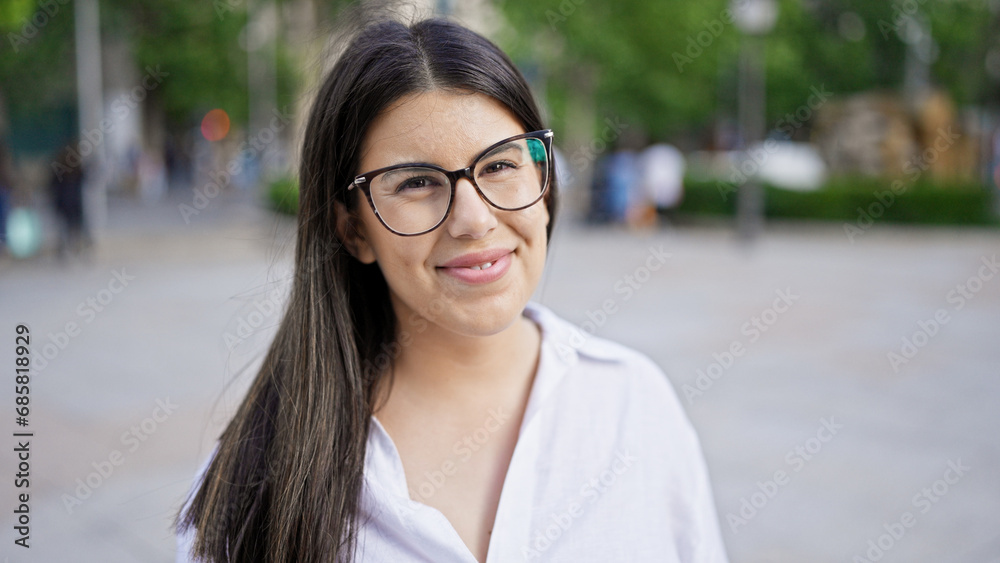 Young beautiful hispanic woman wearing glasses smiling happy in the streets of Madrid