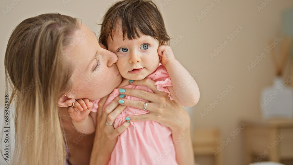 Mother and daughter sitting on bed kissing at bedroom Mother and daughter sitting on bed kissing at bedroom