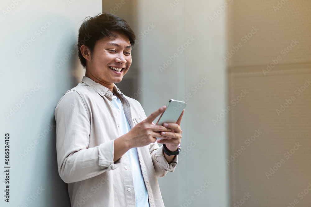 Positive chinese guy employee have break, using phone outdoors Positive chinese guy employee have break, using phone outdoors