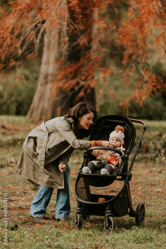 Young woman with cute baby girl in baby stroller at the autumn park © BGStock72