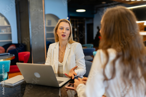 Employees cooperate for teamwork at shared modern workspace. Female managers talk during break at shared workspace in business company
