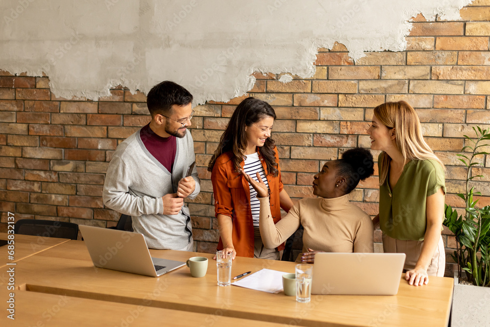 Young multiethnic startup team working by the brick wall in the industrial style office