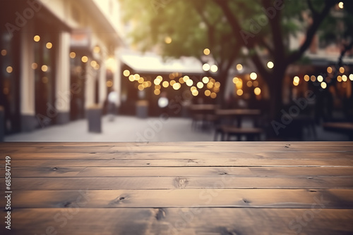 An empty wooden table with a blurred street cafe in the background with big trees, dark wooden chairs and tables, and garlands