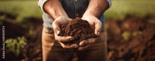 Dark soil in farmer hands. banner. Male hands touching soil on the field. photo
