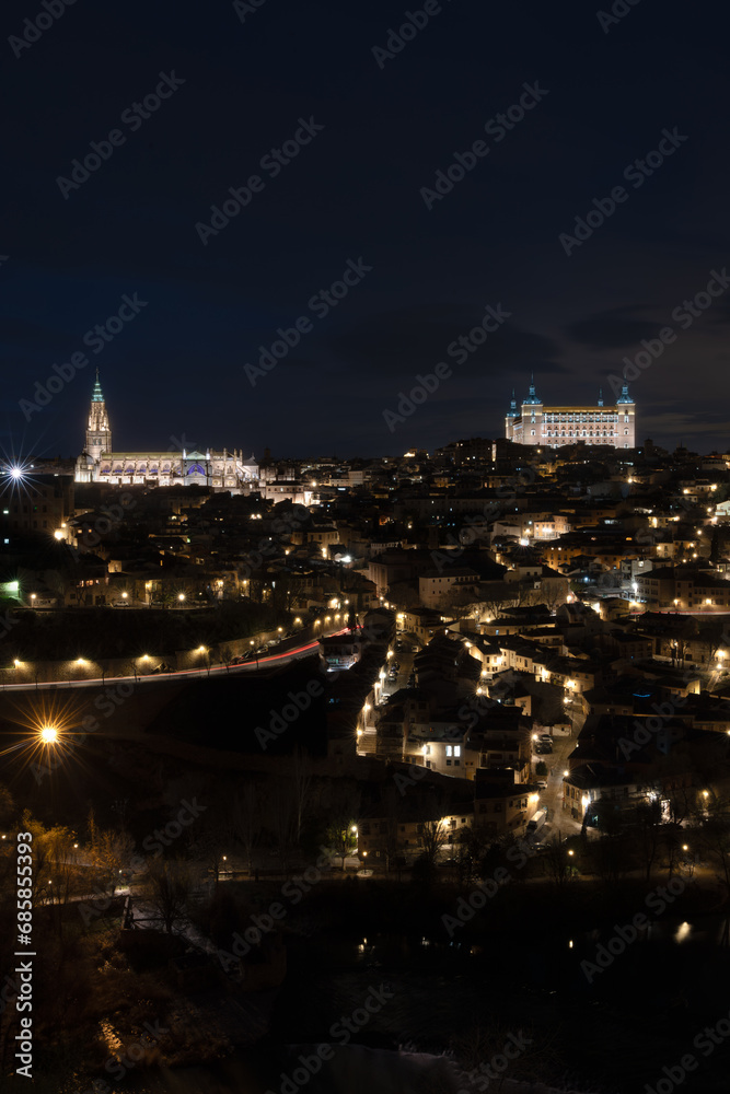Historic center of Toledo, Spain, at night with the light of street lamps and the cathedral of Santa María and the Royal Alcázar (army museum today) illuminated. UNESCO World Heritage Site
