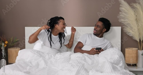 Furious disappointed african american dark skinned woman wife arguing blaiming her husband in treason unhappy young black family concept sitting in bed in the morning. Female gesticulating shouting. photo