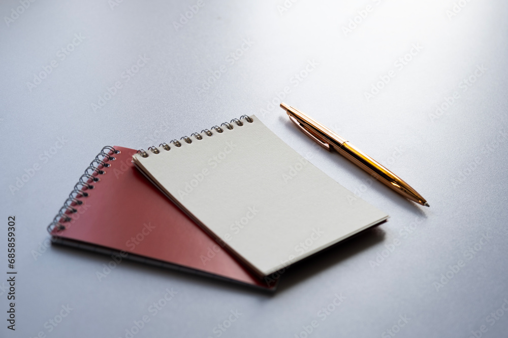 Side view on two small notepads and golden pen on the table Side view on two small notepads and golden pen on the table