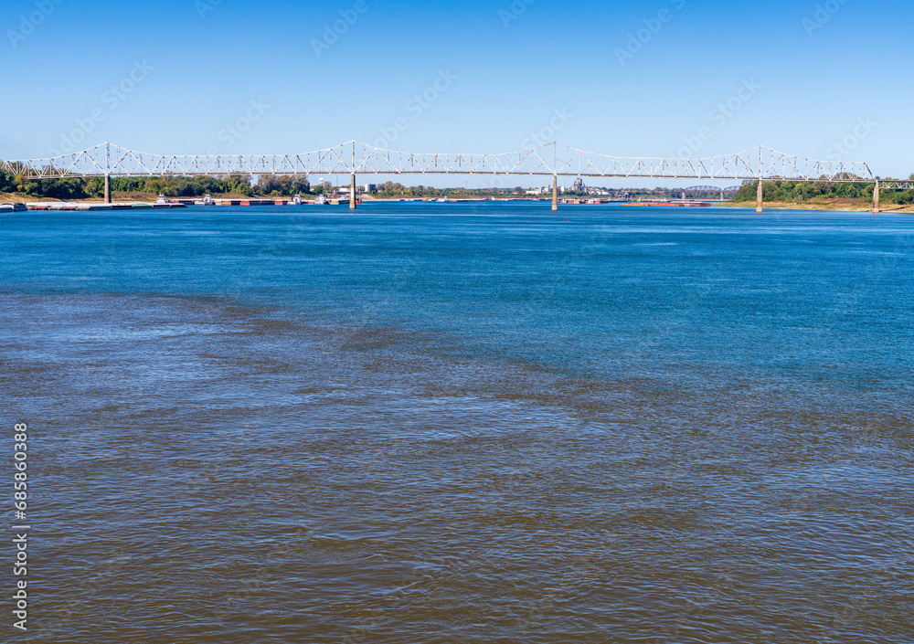 Barges wait at the confluence of the blue Ohio river and brown Mississippi river at Cairo with blue and brown muddy streams mixing