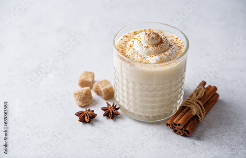 Eggnog with cinnamon decorated with whipped cream in a glass © nata_vkusidey