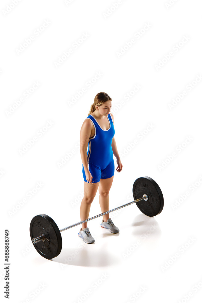 Full-length of professional athlete, young woman training, lifting heavy weight, barbell against white background. Concept of sport, strength, gym, healthy lifestyle, power, endurance, weightlifting. Full-length of professional athlete, young woman training, lifting heavy weight, barbell against white background. Concept of sport, strength, gym, healthy lifestyle, power, endurance, weightlifting.