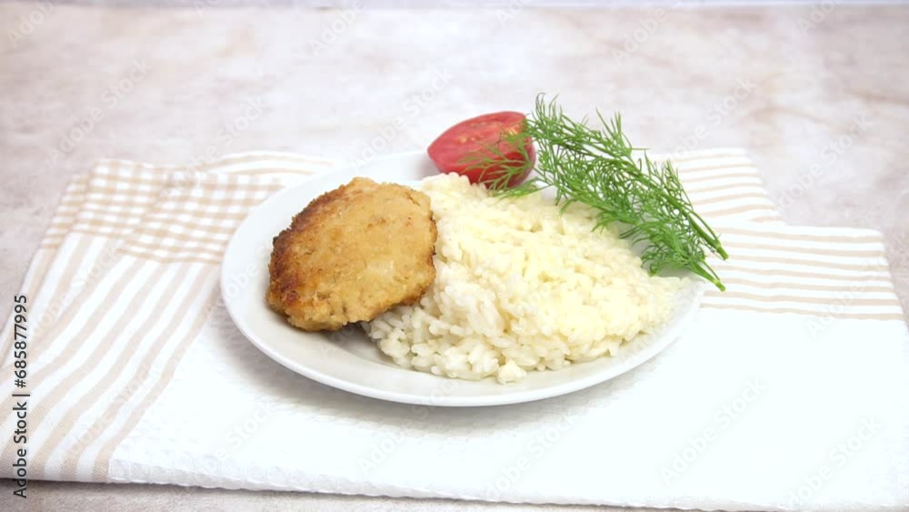 Hot fish cutlet made from minced red fish with a side dish of white rice and a slice of tomato on a plate. Ready dish. Home cooking. Hot fish cutlet made from minced red fish with a side dish of white rice and a slice of tomato on a plate. Ready dish. Home cooking.