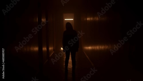 Silhouette woman walks along a dark corridor. Orange light. photo