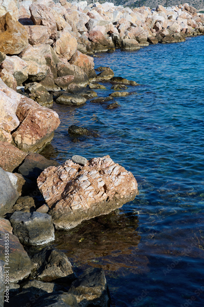 Rocky shore washed by azure sea, vertical