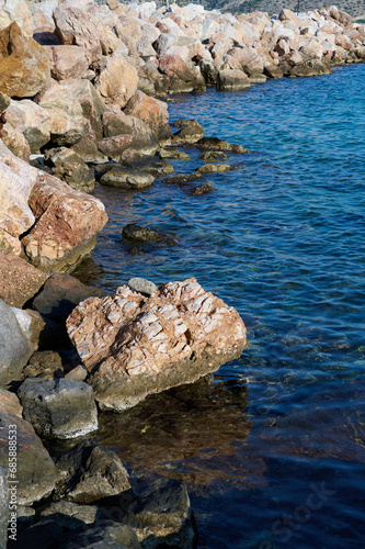 Rocky shore washed by azure sea, vertical