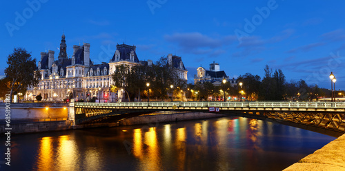 City Hall of Paris and bridge D'Arcole across Seine river at night, France.