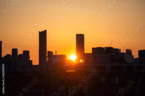 Downtown Toronto at sunrise, with warm golden light in the sky behind silhouettes of the skyline buildings