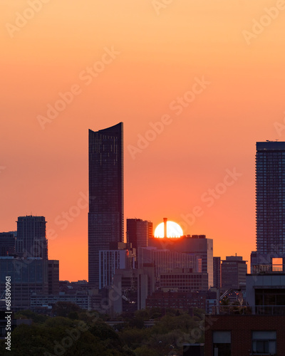 Downtown Toronto at sunrise, with warm golden light in the sky behind silhouettes of the skyline buildings