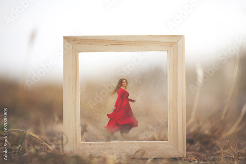 woman dressed in red running away through a surreal frame in the middle of nature photo