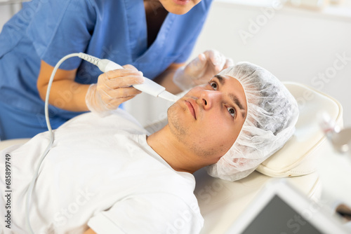 Female cosmetic doctor deftly wields Skin Scrubber attachment, carefully treating gentleman's skin during procedure.