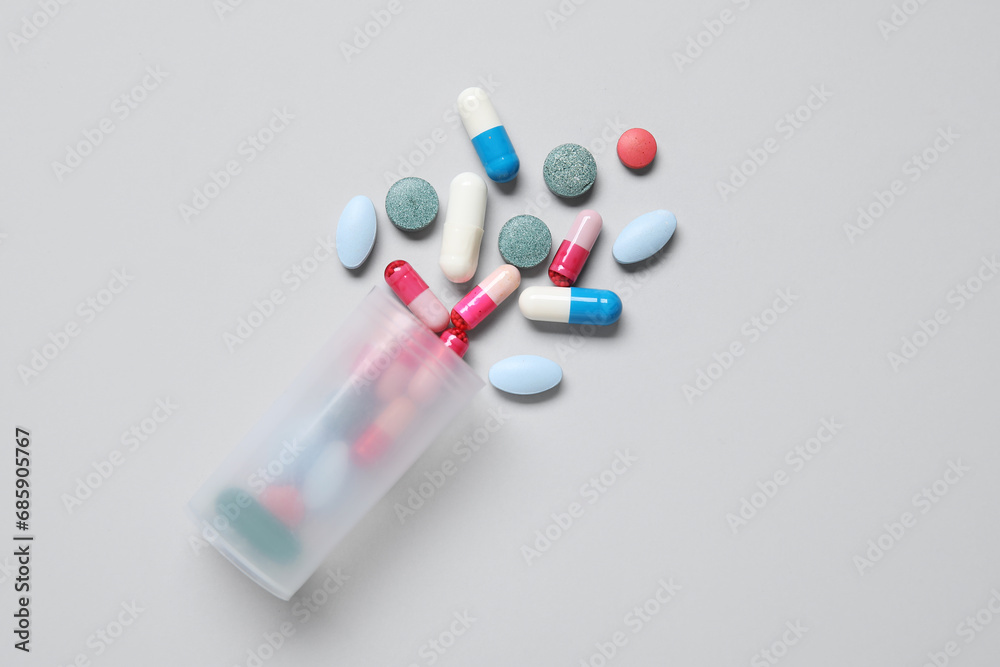 Jar with different scattered pills on grey background Jar with different scattered pills on grey background