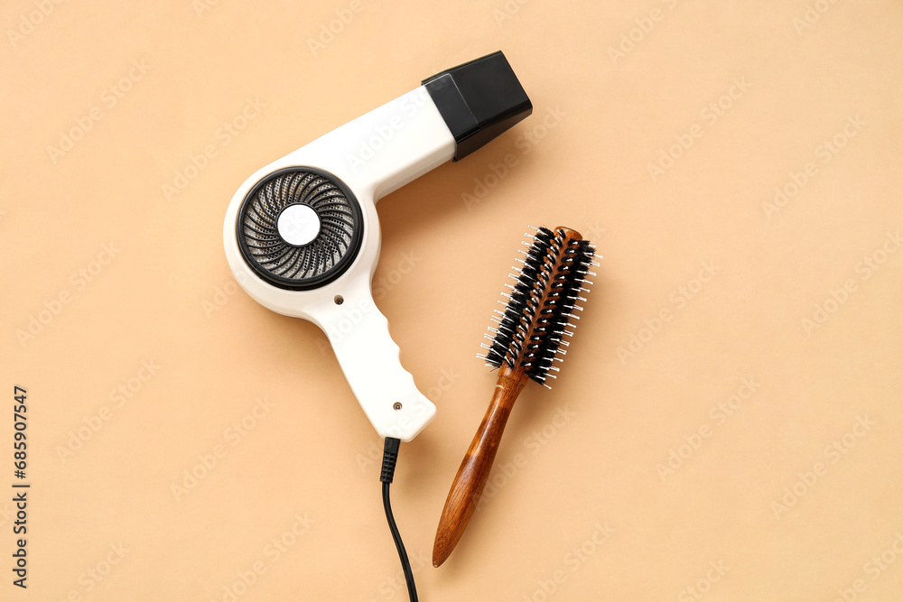 Fototapeta premium Hair dryer and brush on beige background