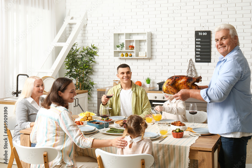 Mature man bringing turkey at festive table with his family on Thanksgiving Day Mature man bringing turkey at festive table with his family on Thanksgiving Day