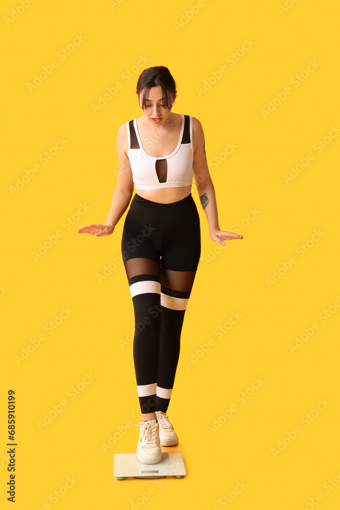 Beautiful shocked woman with scales on yellow background. Weight loss concept Beautiful shocked woman with scales on yellow background. Weight loss concept