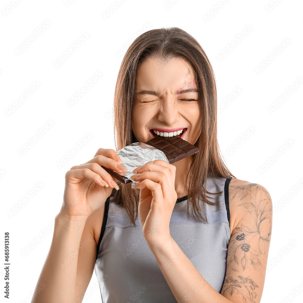 Young woman eating chocolate bar on white background