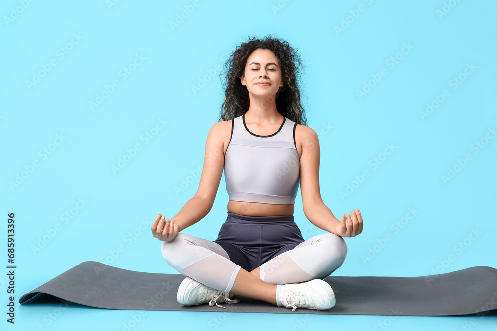 Young African-American woman meditating on blue background