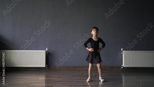 Child girl standing in black sport bodysuit in dancing studio during training posture. 4 5 years old preschool age. Healthy physical development  photo
