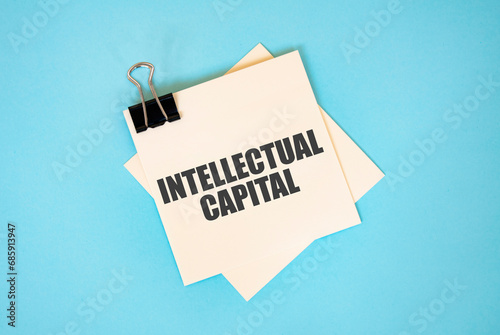 Text Intellectual Capital on sticky notes with copy space and paper clip isolated on red background. Finance and economics concept.