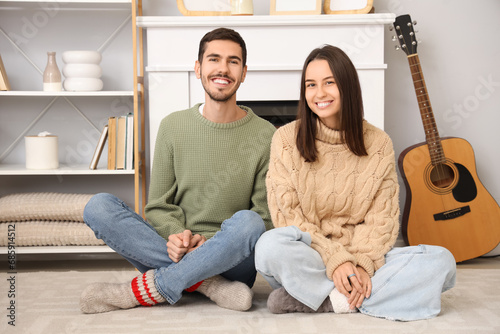 Loving couple sitting near fireplace at home on winter day
