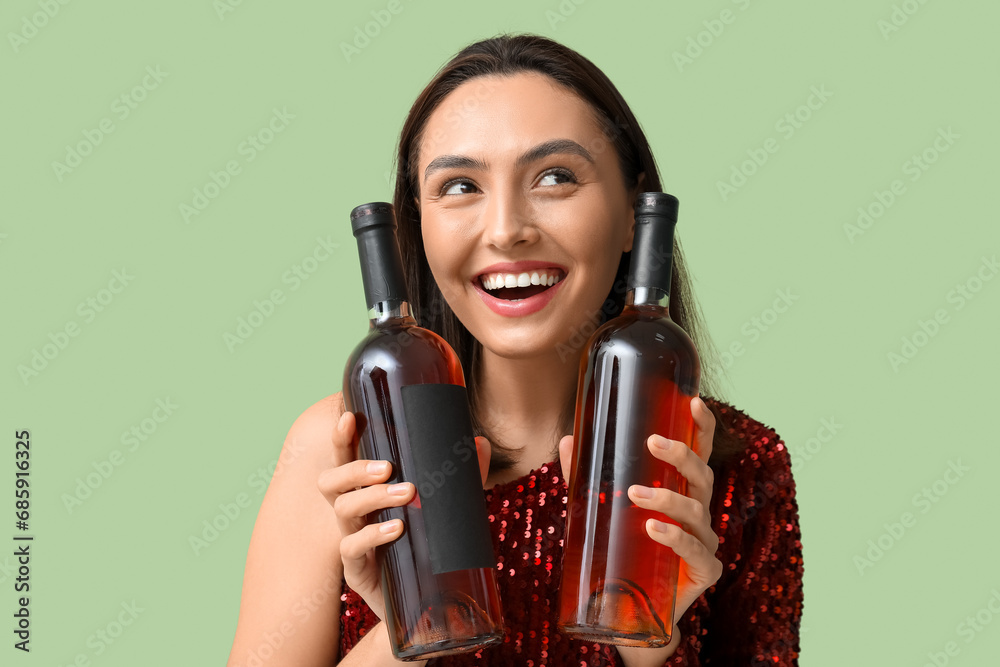 Beautiful young woman with bottles of wine on green background Beautiful young woman with bottles of wine on green background