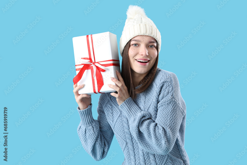 Young woman with Christmas gift on blue background Young woman with Christmas gift on blue background