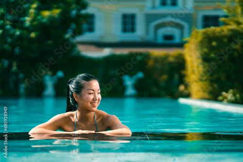 Young asian woman relaxing in the water  Beautiful girl relaxing at overwater infinity pool luxury resort. Spa  wellness  swimming.