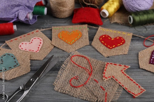 Bunting flags made with burlap fabric and sewing tools on wooden table, closeup