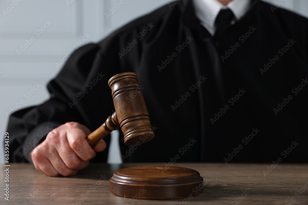 Judge with gavel sitting at wooden table, closeup Judge with gavel sitting at wooden table, closeup