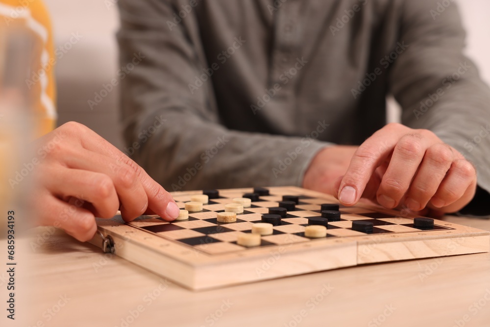 Couple playing checkers at wooden table, closeup Couple playing checkers at wooden table, closeup